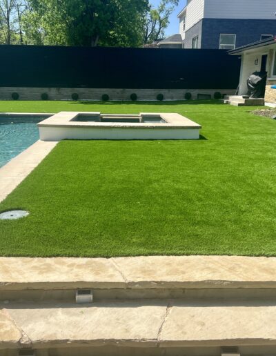 Texas Turf Design: Lush green turf lawn and pool area with outdoor structures and landscaping.