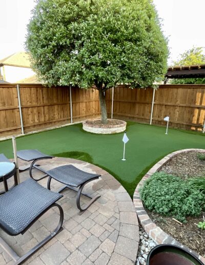 Texas Turf Design putting green and landscape design with trees, bushes, and artificial turf.