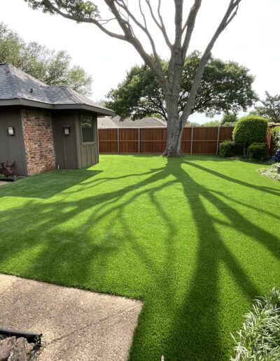 Lush green artificial turf lawn and landscaping by Texas Turf Design.